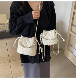 Détail de sacs seaux matelassés crème avec poignées en perles et chaînes dorées