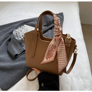 Close-up of brown litchi pattern bucket bag with silk scarf detail and golden hardware