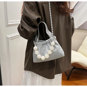 Detail of silver grey cloud bag with glossy pearl handle and metallic chain strap
