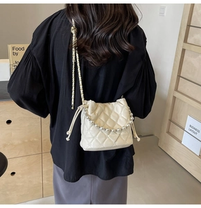 Détail du sac seau matelassé crème avec coutures en étoile et anse en perles