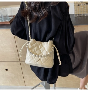 Détail du sac seau matelassé crème avec poignée en perles et bandoulière en chaîne
