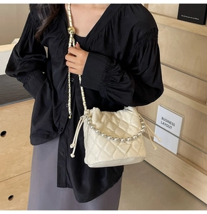 Détail du sac seau matelassé blanc avec chaîne en perles et bandoulière en métal doré