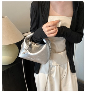 Dettaglio borsa a mano argento metallizzato con texture plissettata e catena a sfere