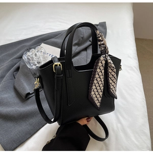 Close-up of black pebble leather bucket bag with gold hardware and geometric scarf detail