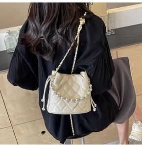 Détail du sac seau matelassé beige avec poignée en perles et bandoulière en chaîne