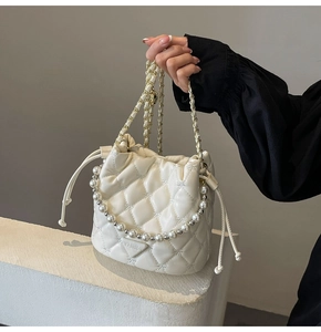 Détail d'un sac seau matelassé blanc avec poignée en perles et bandoulière en chaîne