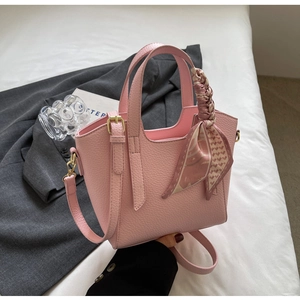 Detail of pink lychee leather handbag featuring a stylish silk scarf wrap and gold hardware