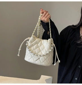 Détail du sac seau matelassé crème avec poignée en perles et chaîne dorée chic