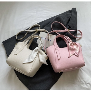Close-up of lychee grain leather bucket bags with scarf-wrapped handles and straps