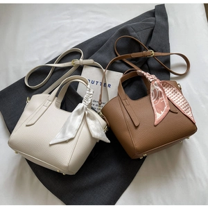 Detail of leather bucket bags with silk scarf handles on a dark blazer background