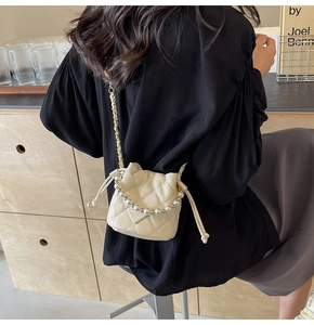 Détail du sac seau crème avec poignée en perles et texture matelassée élégante