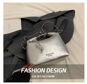 Dettaglio della borsa a mano argento con texture stropicciata, catena e perle decorative