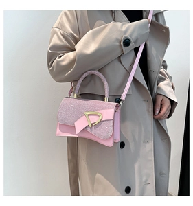 Close-up of pink sequined flap handbag with gold triangular buckle worn with a beige coat