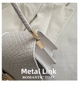 Details einer weißen gewebten Tasche mit eleganten goldenen Metallbeschlägen und Glanzfinish