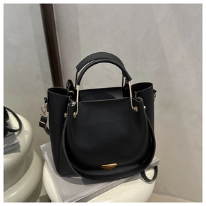 Detail view of the black tote bag featuring golden triangle hardware and smooth faux leather