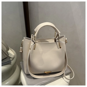 Detail of off-white leather bucket handbag with gold triangle logo and top handles