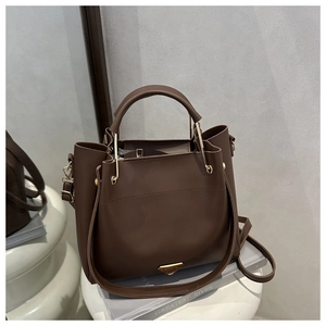 Detail of dark brown tote bag with metal triangle logo and matte leather texture