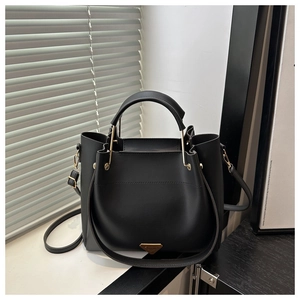 Detail of black leather handbag featuring a golden triangle logo and metallic hardware