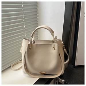 Detail of cream white leather bucket bag with gold triangular logo and handle