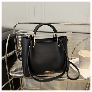 Close-up of black matte leather tote with golden triangle logo on a metal rack