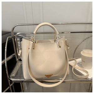 Detail of cream white tote bag on metal rack with gold triangle logo and top handle