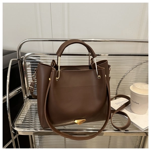 Detailed macro view of dark brown leather handbag with luxury gold triangular logo plate