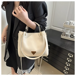 Detail of cream bucket bag with metal handle and classic triangle logo accent