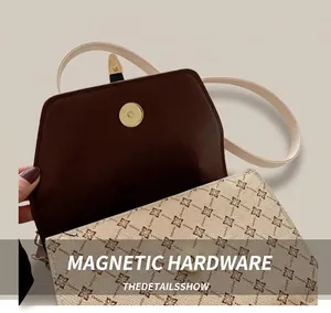 Close-up of golden magnetic buckle on vintage beige clover print handbag with suede interior