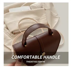 Detail of dark brown retro handbag featuring a comfortable handle and metal buckle accent