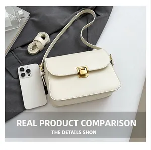 Detail shot of ivory vintage crossbody bag with gold lock next to a smartphone