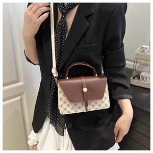 Detalle de bolso bandolera elegante con patrón vintage y cierre giratorio metálico