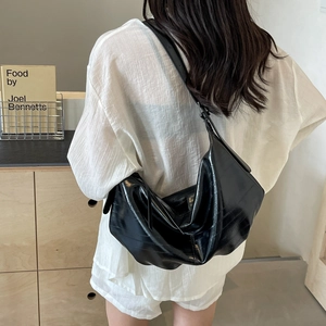 Minimalist black leather tote bag with wide adjustable shoulder strap worn by a model