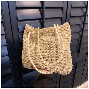 Detail of hand-held beige crochet straw tote bag showing fine woven texture and pattern