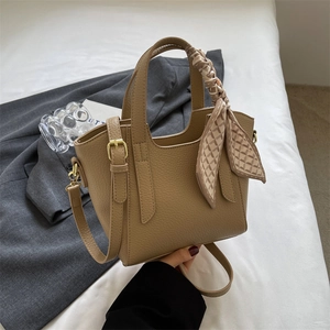 Minimalist khaki lychee grain bucket bag with decorative silk scarf and gold hardware