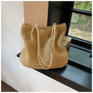 Close-up of woven straw tote bag with delicate texture and long shoulder handles