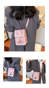 Detailed view of pink crossbody phone bag featuring a metal pendant and textured flap