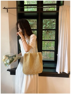Close-up of a large handmade straw tote bag with natural woven texture and shoulder straps