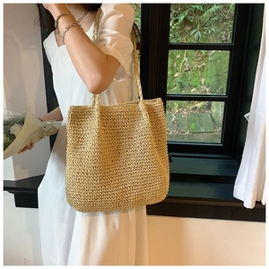 Close-up of large woven straw tote bag featuring detailed hand-braided texture and straps