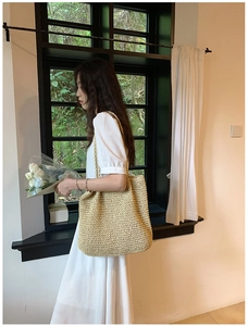 Detail of hand-woven straw tote bag with long shoulder strap in a summer natural style