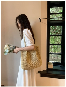 Detail of hand-woven straw tote bag showing tight crochet texture and dual braided handles