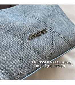 Close-up of diamond quilted denim fabric with a metallic brand logo on the bag