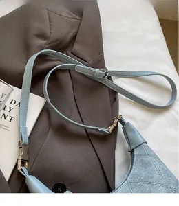 Detail view of adjustable denim shoulder strap with silver metal buckle on blue crossbody bag