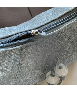 Detail of silver zipper head and gray-blue quilted fabric texture of the handbag