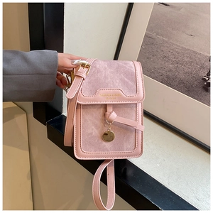 Pink mini crossbody bag featuring textured leather panels and a gold circular pendant
