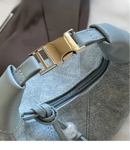 Detail shot of the polished metal clasp and denim quilted texture on a vintage bag