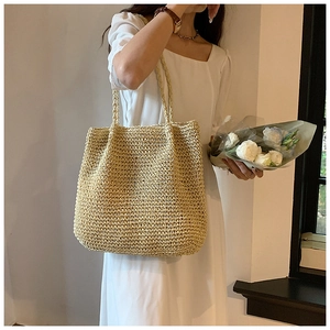 Detail of hand-woven large straw tote bag featuring natural texture and long shoulder straps