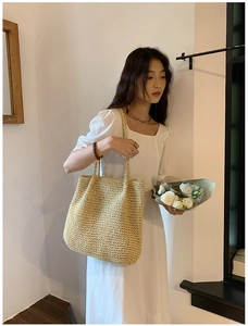 Close-up of a woven straw tote bag in beige with long handles for casual beach style
