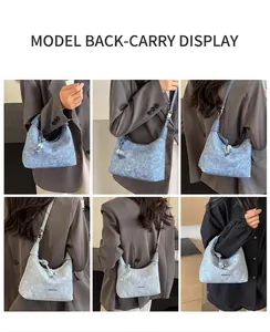 Detail view of light blue denim shoulder bag with silver hardware and plush pendant