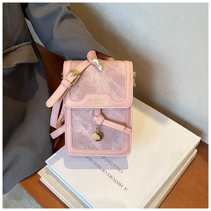 Detail of pink leather and denim crossbody bag with adjustable strap and gold metal pendant