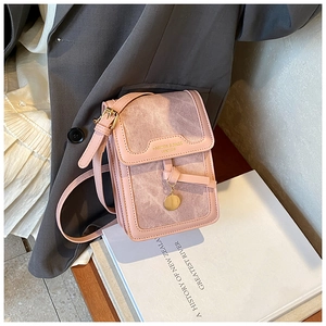 Detail of pink faux leather crossbody phone bag with gold lettering and charm on grey blazer